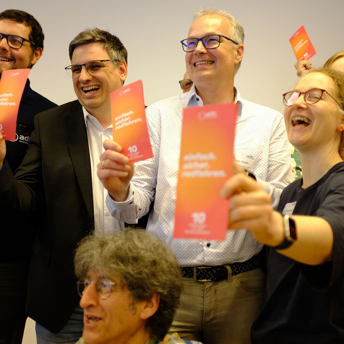 Vier Personen halten einen Kampagnenflyer hoch. 