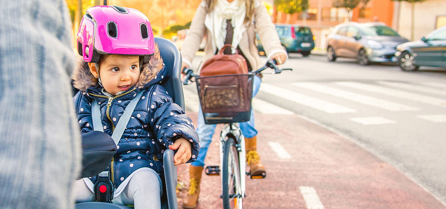 Lttle girl with helmet on head sitting in bike seat