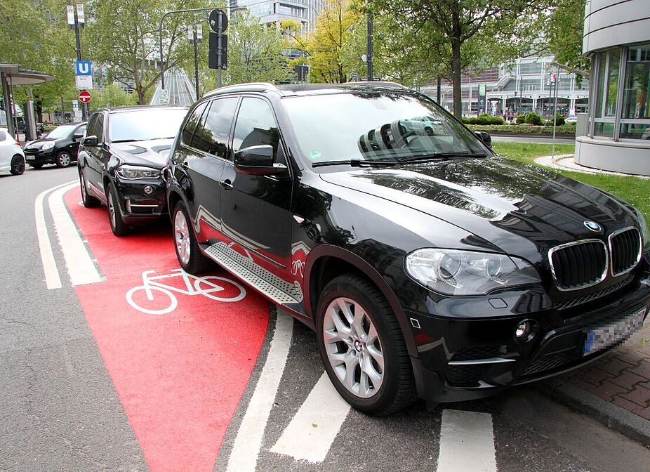 SUV parkt auf Radfahrstreifen Schwarzer SUV parkt auf rot markiertem Radfahrstreifen